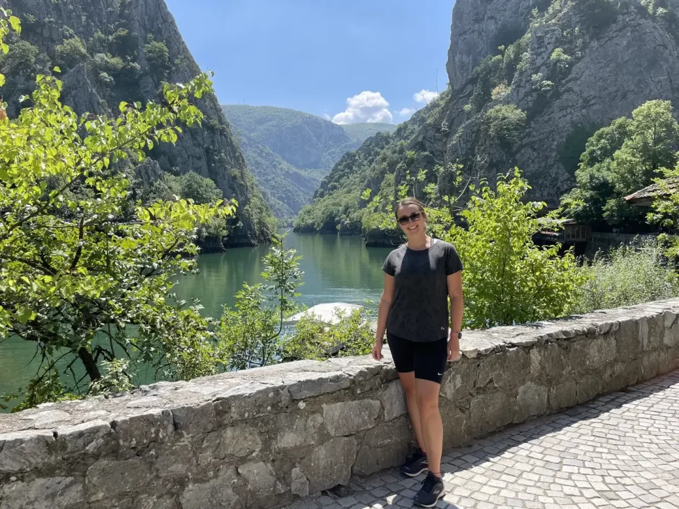 Woman with a canyon, peaks and a lake, behind her with bright blue skies in Matka Canyon North Macedonia