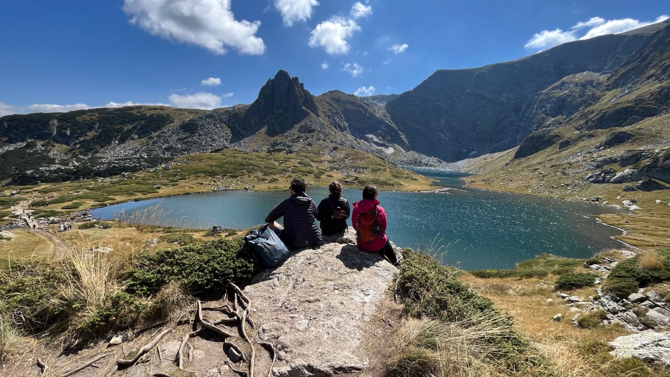friends sitting by a lake with surrounding mountains in Bulgaria